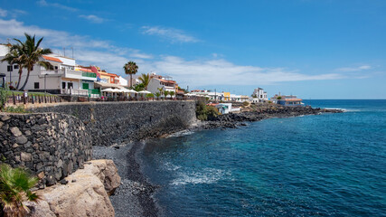 Fototapeta premium Charming little coastal resort in the south of the island with large promenade lined up with fish restaurants, terraces and bars in La Caleta, Costa Adeje, Tenerife, Canary Islands, Spain