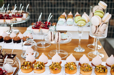 Candy bar. Beautiful multi colored decorated candy table baked sweet tasty cupcake cupcakes on a party. Beautifully decorated catering banquet table with different candy sweet delicacy.