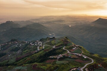 Winding curvy rural road with light trail leading fog through,thai countryside.