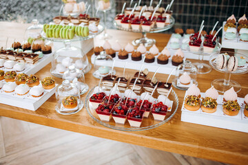 Small cakes with white and red filling, decorated with berries on the table. 
