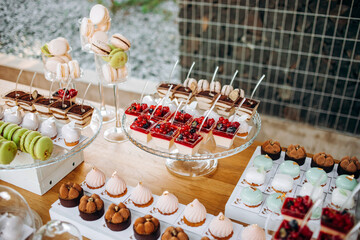 Candy bar. Beautiful multi colored decorated candy table baked sweet tasty cupcake cupcakes on a party. Beautifully decorated catering banquet table with different candy sweet delicacy.
