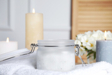 Jar of natural exfoliating salt scrub on white towel