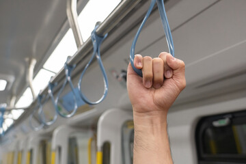 A close up of a hand holding a handgrip or handle ring on the fast train inside the service...