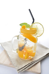 cold iced mango peach fruit juice with lemon mint leaf in glass jar white background asian beverage halal menu