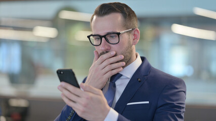 Obraz na płótnie Canvas Disappointed Businessman Reacting to Loss on Smartphone