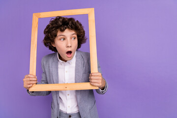 Photo of crazy excited shocked little guy hold frame look empty space wear grey suit isolated violet color background - Powered by Adobe