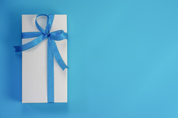 White gift box with blue ribbon on blue background