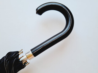 Closeup of a black closed umbrella isolated on a white background