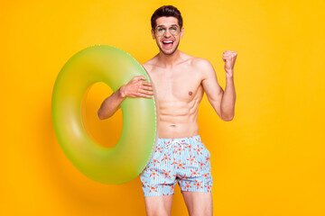 Photo of attractive cool young guy shirtless arm dark glasses smiling holding water circle rising fist isolated yellow color background