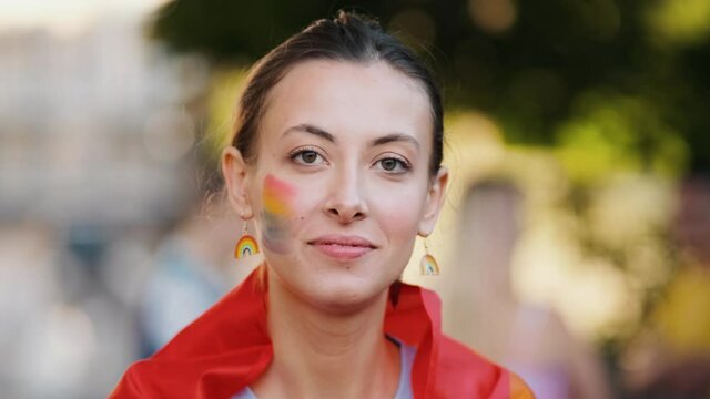 A positive woman with rainbow make-up is sending an air-kiss to the camera during pride gay parade