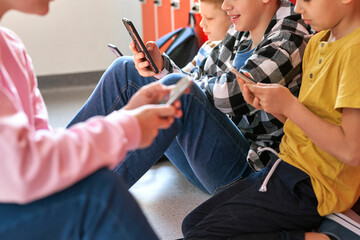Close up teenagers texting on cell phone in school corridor