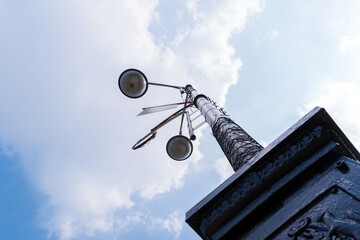 Vintage iron street lamp close-up against a blue sky on a sunny day.
