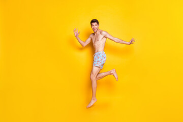 Fototapeta na wymiar Full length photo of funny brunet young man jump wear shorts isolated on yellow background