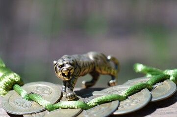Tiger figurine close-up. Next to it are Chinese coins tied in a knot.