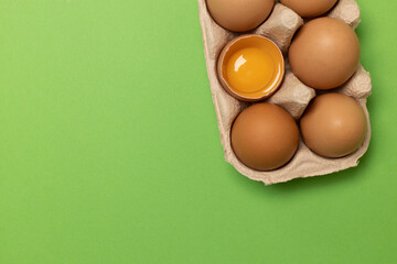 OrganicEaster brown chicken eggs in eco basket and one egg on green background, flat lay, copy space.