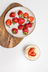 Strawberry tiramisu cheesecakes with fresh strawberries in plate with a delicate tiramisu dessert on white table, copy space, top view