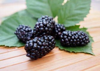 Selected  berries gardenblackberries  and leaves on a wooden surface