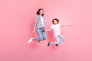 Fototapeta na wymiar Full length body size view of attractive trendy cheerful sisters jumping having fun isolated over pink pastel color background