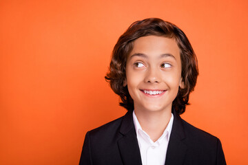 Photo of young happy dreamy charming boy look empty space curious good mood isolated on orange color background