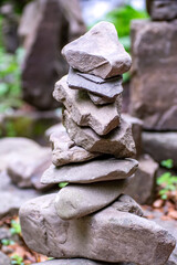 Close-up of a stack of stones in perfect balance in a mountain forest. Rock pyramid, rock balancing art. Meditation, balance, peace. Hobby. Vertical photo.