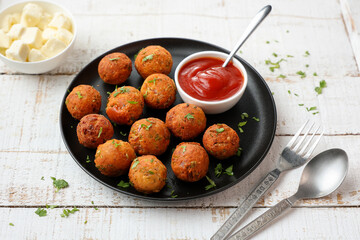 Fried potato cheese balls or croquettes cottage cheese Paneer ball with tomato sauce on black plate over dark background. fast food, top view meat ball.