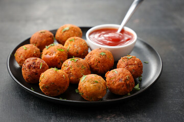 Fried potato cheese balls or croquettes cottage cheese Paneer ball meat balls with tomato sauce on black plate over dark background. fast food, top view 