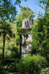 Water tower at lower pond in South Cultures arboretum. Close-up. In foreground are palms and exotic plants. Tower was built at beginning of 20th century on Sirius (Adler). Sochi, Russia - May 19, 2021