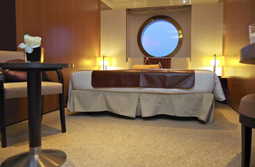 View into luxury bedroom with double bed and porthole window and seating in outside exterior...