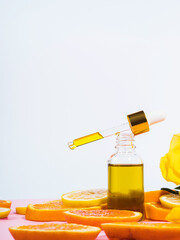 Vitamin C serum bottle with dropper on pink background with orange citrus slices