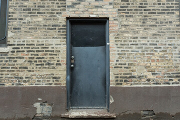 Vintage brick building with black door in urban setting