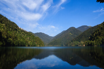 view of the riza lake surrounded with mountains covered with forest under the blue sky