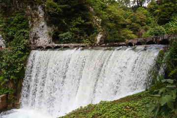 waterfall of an old power plant dam in caucasus mountains