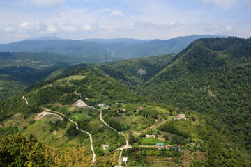 sandy road and small village house in caucasus mountains covered with forest