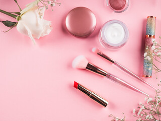Obraz na płótnie Canvas Trendy make up brushes with products on pink background with gypsophila flowers