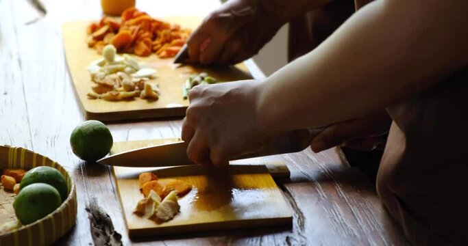 Close up of two women cutting herbs, roots and spices for traditional homemade Jamu drink- Indonesian herbal beverage with natural ingredients: turmeric, ginger, lime, lemongrass, tamarind, lemon