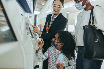 Attendant helping a family doing the self check-in at the airport