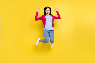 Full length photo of funky brunette young lady jump wear pink sweater jeans isolated on yellow background