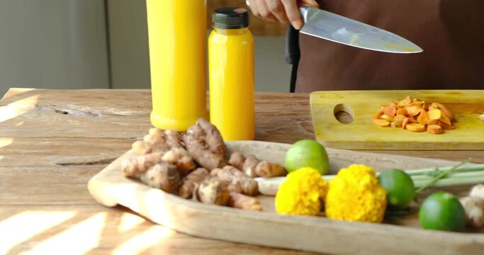 Close up of two women cutting herbs, roots and spices for traditional homemade Jamu drink- Indonesian herbal beverage with natural ingredients: turmeric, ginger, lime, lemongrass, tamarind, lemon
