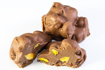 Shapeless chocolate with milk and pistachios on a white background.