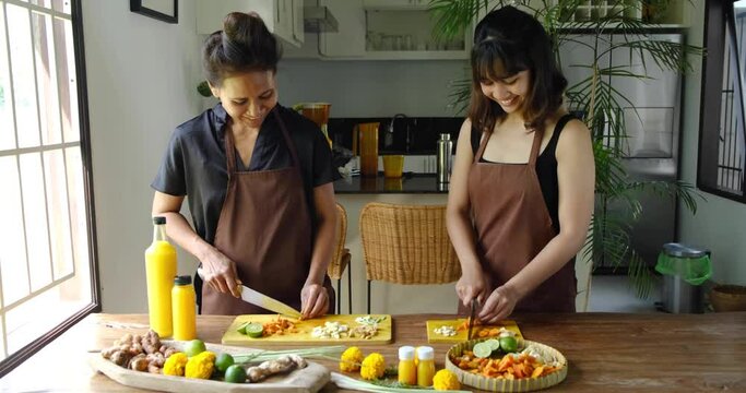 Mother teaching her daughter how to prepare traditional homemade Jamu drink- Indonesian herbal beverage with natural ingredients: turmeric, ginger, lime, lemongrass, tamarind.