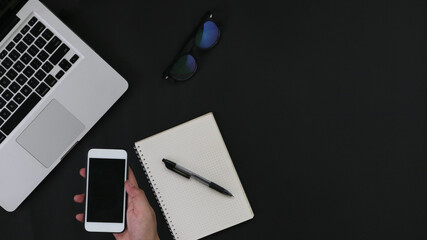 hand with smartphone laptop notebook on black background