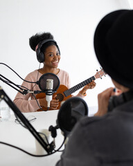 Fototapeta na wymiar Podcasters, African American and European woman with headphones and microphone recording a podcast in a recording studio, Millennial black woman and white woman creating audio content, confident women