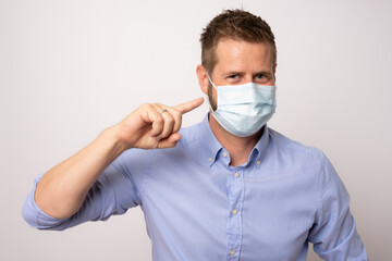 Portrait of handsome young businessman with surgical medical mask looking at camera.