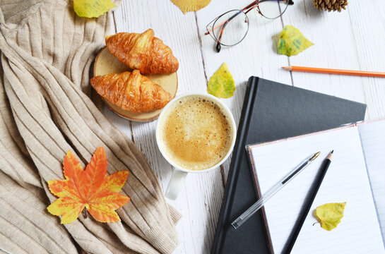 Cup of coffee with autumns leaves, diary and book on the white wooden texture. Back to school. September, October. Write and read, study  in relaxing atmosphere.  Work from home. Quarantine stay home 