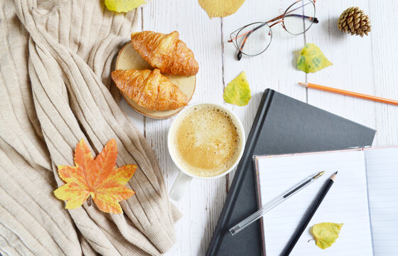 Cup of coffee with autumns leaves, diary and book on the white wooden texture. Back to school. September, October. Write and read, study  in relaxing atmosphere.  Work from home. Quarantine stay home.