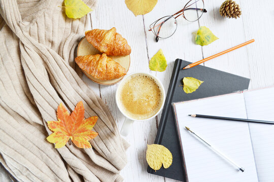 Cup of coffee with autumns leaves, diary and book on the white wooden texture. Back to school. September, October. Write and read, study  in relaxing atmosphere.  Work from home. Quarantine stay home 