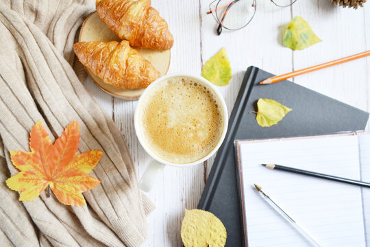 Cup of coffee with autumns leaves, diary and book on the white wooden texture. Back to school. September, October. Write and read, study  in relaxing atmosphere.  Work from home. Quarantine stay home 