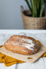 women's hands hold bread against the background of a light apron, bread with a crispy crust is beautiful and appetizing, delicious bread lies on a wooden cutting board and a kitchen knife, homemade