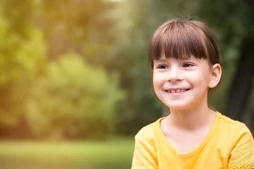 Foto op Canvas Gelukkig klein meisje in een geel t-shirt kijkt weg op een groene achtergrond © Albert Ziganshin