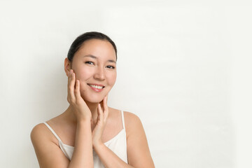 an attractive young Asian woman with perfect skin on a white background. the concept of facial care, prevention of aging and aging of the skin.